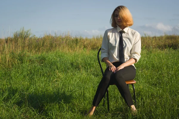 Beauty woman sitting in the armchair at the field — Stock Photo, Image