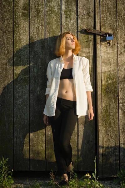 木造の納屋を背景に立っている女の子 — ストック写真