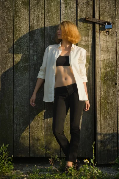 Girl  standing against a background of a wooden barn — Stock Photo, Image