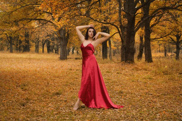 Chica en un vestido rojo bailando en el bosque de otoño — Foto de Stock