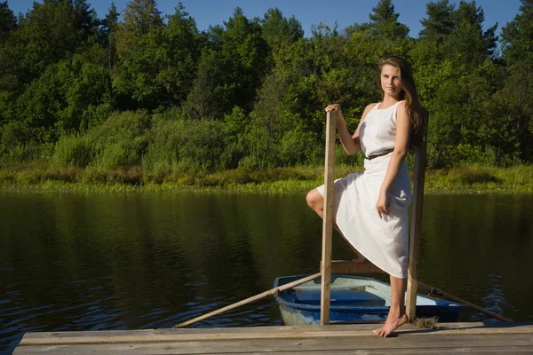 Ontspannen jonge vrouw op houten pier op het meer — Stockfoto