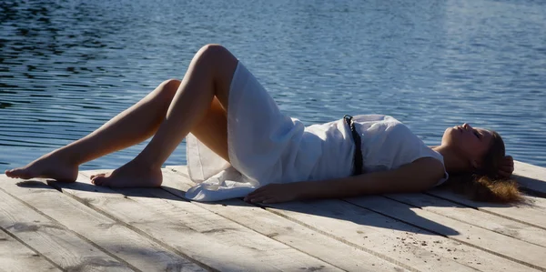 Relaxante jovem mulher no cais de madeira no lago — Fotografia de Stock