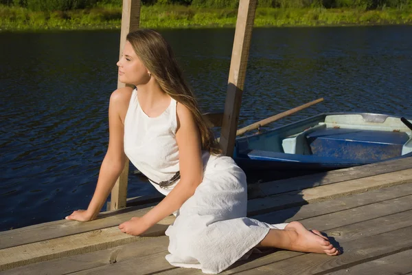 Relaxing young woman on wooden pier at the lake — Stock Photo, Image