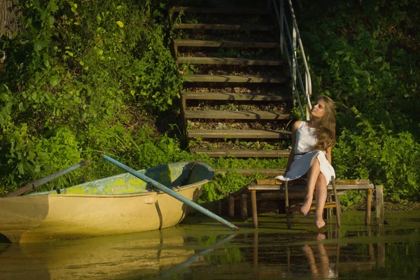 Relaxační mladá žena na dřevěném molu u jezera — Stock fotografie