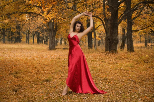 Chica en un vestido rojo bailando en el bosque de otoño — Foto de Stock