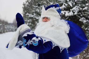 Ded Moroz (Father Frost) with gifts bag in the winter forest