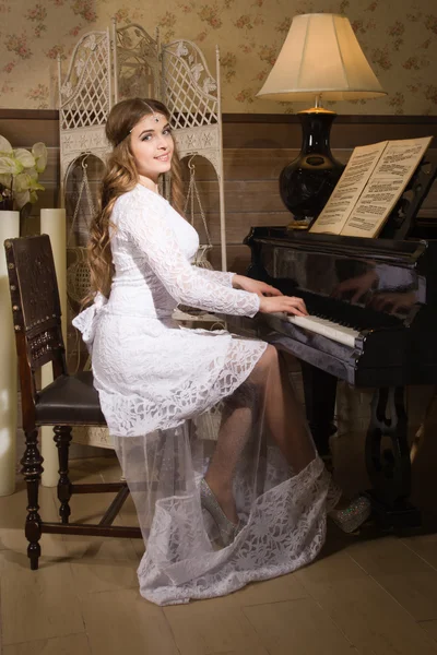 Schoonheid vrouw in avondjurk pianospelen — Stockfoto