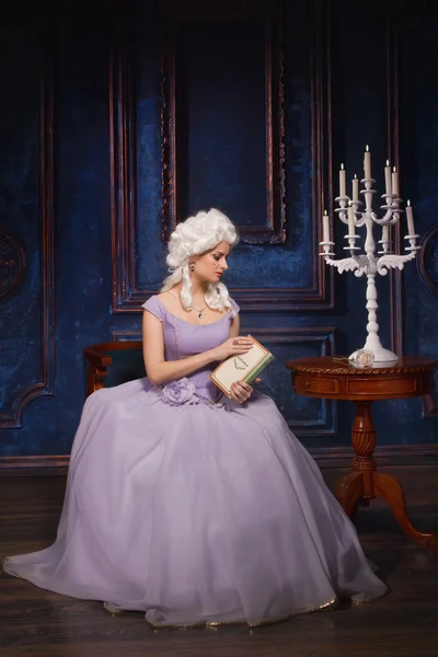 Женщина в платье в стиле барокко и белый парик с книгой — стоковое фото