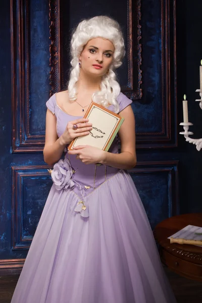 Женщина в платье в стиле барокко и белый парик с книгой — стоковое фото