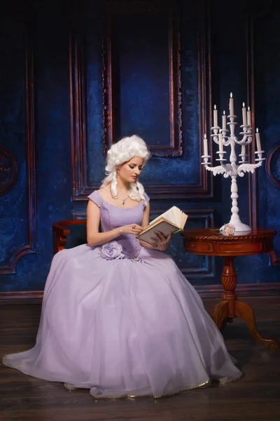 Kvinna i historiska barock stil klänning och vit peruk med en bok — Stockfoto