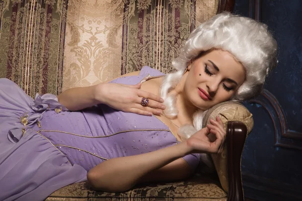 Femme en robe de style baroque historique et perruque blanche sur le canapé — Photo