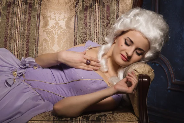 Mulher em estilo barroco histórico vestido e peruca branca no sofá — Fotografia de Stock