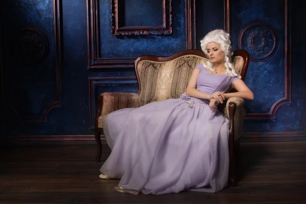Frau in historischem Barockkleid und weißer Perücke auf der Couch — Stockfoto