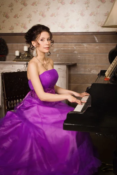 Kvinna klädd i lång spetsklänning spela piano — Stockfoto