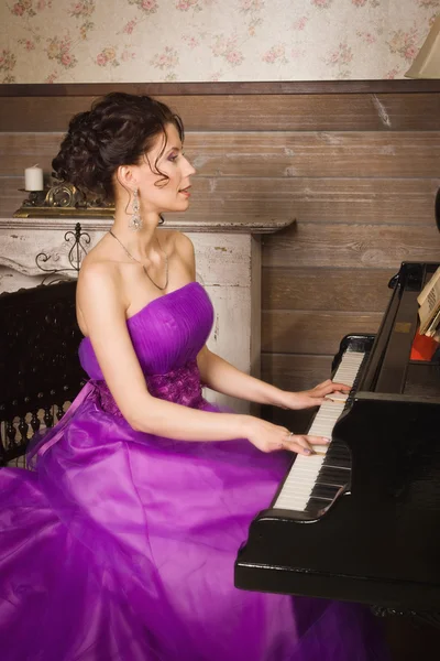 Mulher vestida com vestido de renda longa tocando piano — Fotografia de Stock