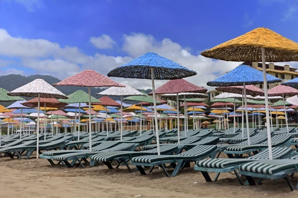 Straw umbrellas with chairs on beach — Stock Photo, Image