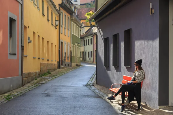 Девочка-подросток сидит на скамейке на улице Старого города — стоковое фото