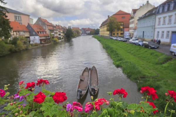 Fluss, Boote, rote Blumen und alte Häuser — Stockfoto