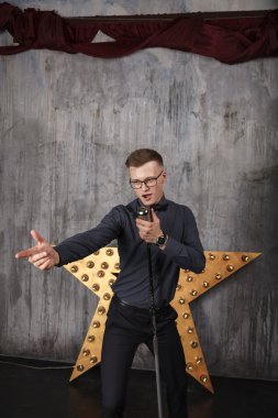 Genç adam mikrofonla şarkı söylüyor.