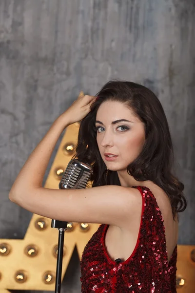 Chica joven en vestido de cóctel rojo con micrófono vintage — Foto de Stock