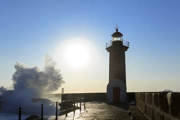 Onda respingo ao pôr do sol perto do farol — Fotografia de Stock