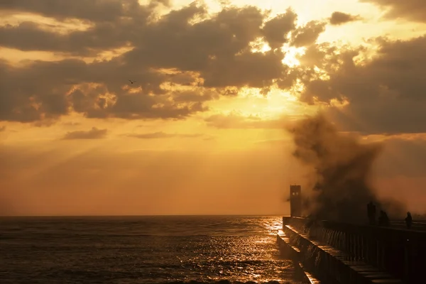 Groupe de pêcheurs sur la jetée près du phare avec éclaboussure de vague — Photo