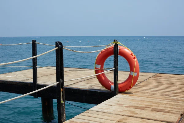 Lifebuoy vermelho no cais de madeira — Fotografia de Stock