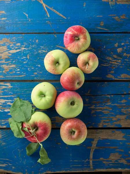 Färska och mogna äpple på blå tabell — Stockfoto