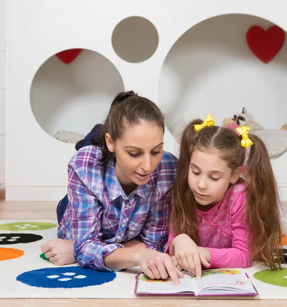 Mor läsning bok med sin dotter hemma — Stockfoto