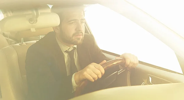 Getöntes Bild des Geschäftsmannes, der Auto fährt. Freiberufler im schwarzen Business-Anzug eilt zur Arbeit, um viele Dinge zu erledigen. — Stockbild Geschäftsmann fährt Auto — Stockfoto