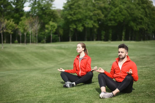 Sport férfi és nő, meditál, park — Stock Fotó