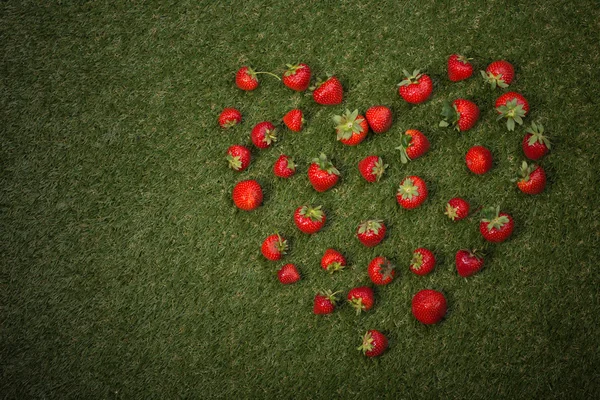 Cuore di fragole su erba verde . — Foto Stock