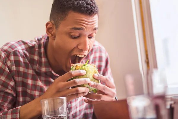 Hombre comiendo hamburguesa vegana en el restaurante — Foto de Stock