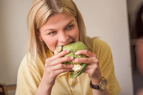 Woman eating vegan burger in restaurant — Stock Photo, Image