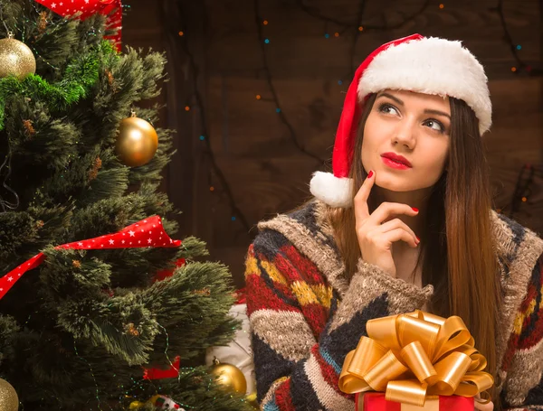 Красивая девушка с подарком возле новогодней елки — стоковое фото