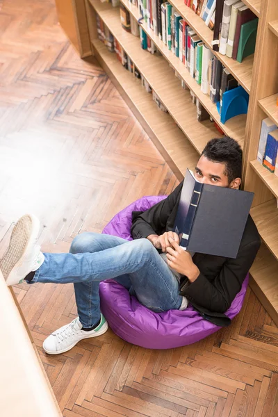 Bello uomo che legge libro in biblioteca — Foto Stock