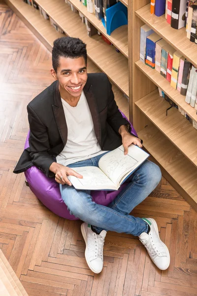 Bello uomo che legge libro in biblioteca — Foto Stock