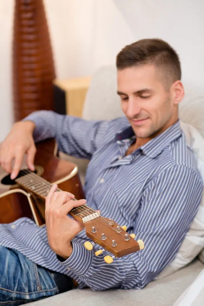 Hombre guapo tocando la guitarra en casa — Foto de Stock