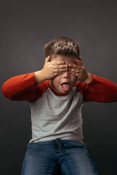 Den lille pojken visar tungan med händerna stängda. Förskolebarn uttrycker känslor i studion — Stockfoto