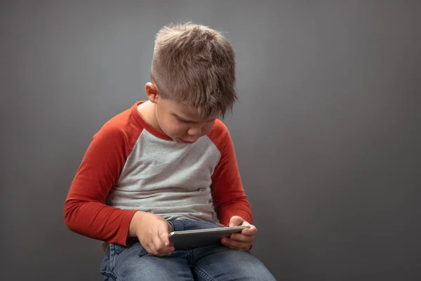 Een kleuter met een mobieltje. Kind in de studio houdt grote smartphone spreken over het met vrienden online. Technologieconcept — Stockfoto