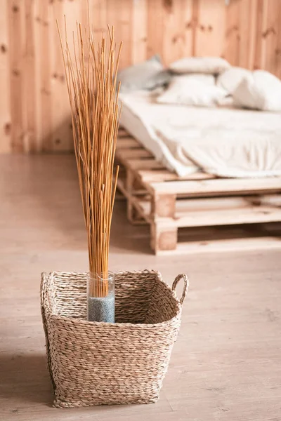 Decoração de casa natural no interior de madeira do quarto. Buquê de paus secos em vaso e cesta de vime no chão — Fotografia de Stock