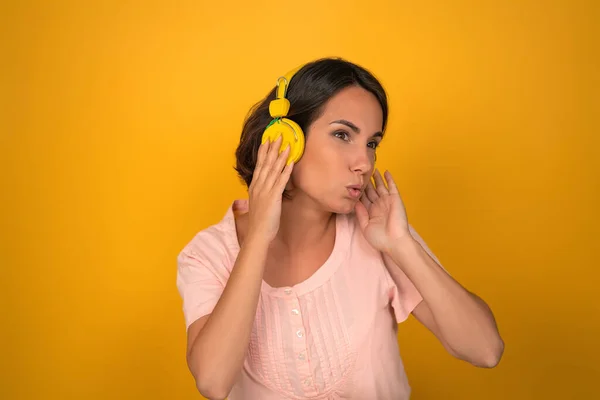 Mladá žena poslouchá hudbu se žlutými sluchátky — Stock fotografie