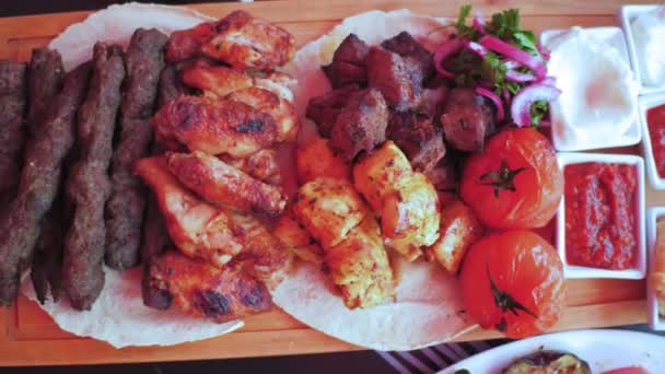 Az örmény konyha áttekintése. Grillezett húsok és zöldségek, valamint szószok, fekszenek egy fa aprítódeszkán. Kiváló minőségű 4k felvételek — Stock videók