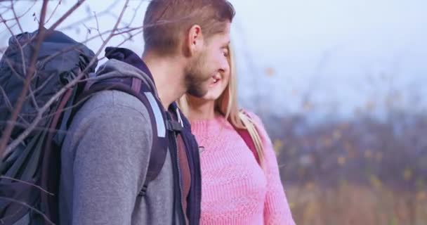 Joyeux couple en pleine nature. Jeune fille blonde sourit. homme caucasien avec sac à dos sur ses épaules sourit. — Video