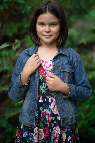 Kleine Mongolin in buntem Anzug und Jeansjacke mit kurzen dunklen Haaren posiert Garten im Hintergrund — Stockfoto