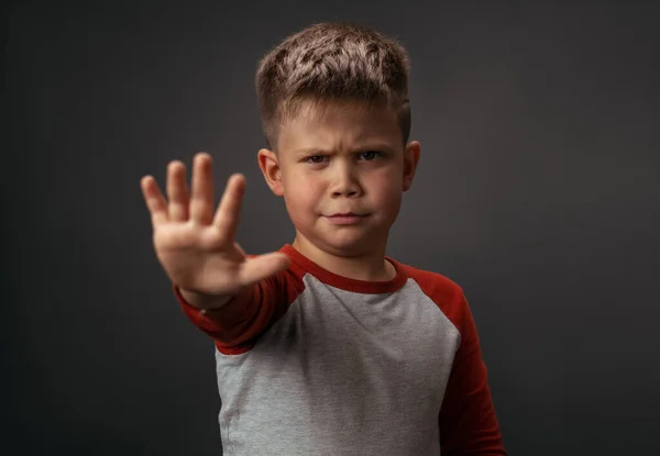 En seriös unge visar stoppskylt. Liten pojke håller en öppen handflata framför honom, gest betyder hålla sig borta från mig. Håll distanskonceptet — Stockfoto