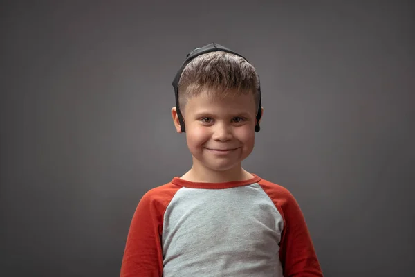 Sonriente chico caucásico con mascarilla en la cabeza. Niño feliz posando sobre fondo gris. — Foto de Stock