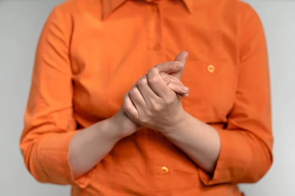 Mulher madura em camisa laranja dobrou as mãos. A fêmea deu as mãos. Um tiro de perto. Isolado em fundo branco. Vista frontal — Fotografia de Stock