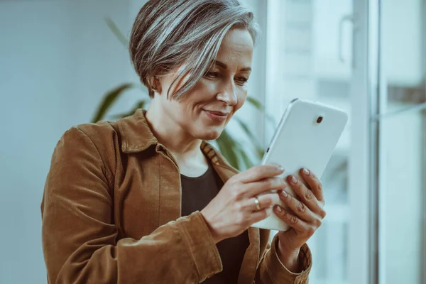 Wanita dewasa yang cantik berkomunikasi secara online pada tablet digital. Tutup tembakan. Pandangan sisi bawah. Konsep gaya hidup — Stok Foto