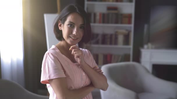 Příjemně se usmívající žena s krátkým účesem. Její ruce složené na hrudi na pozadí obývacího pokoje. — Stock video